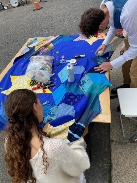 two people adding to a blue patchwork quilt
