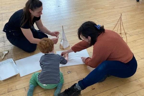 2 adults and 1 child making a lantern from willow and paper 