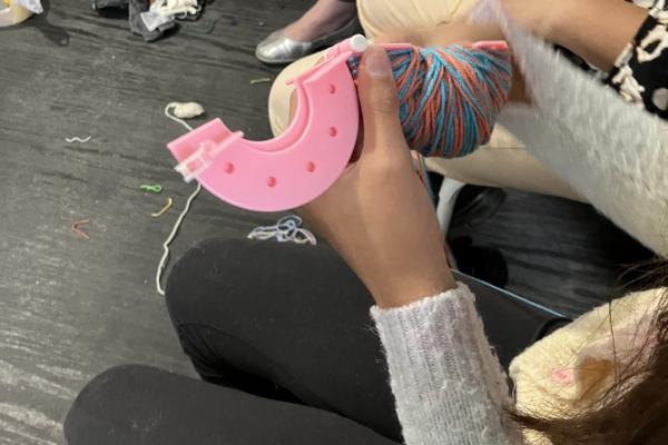 hands and pom pom maker with yarn