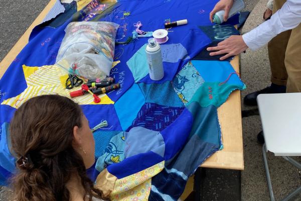 two people adding to a blue patchwork quilt